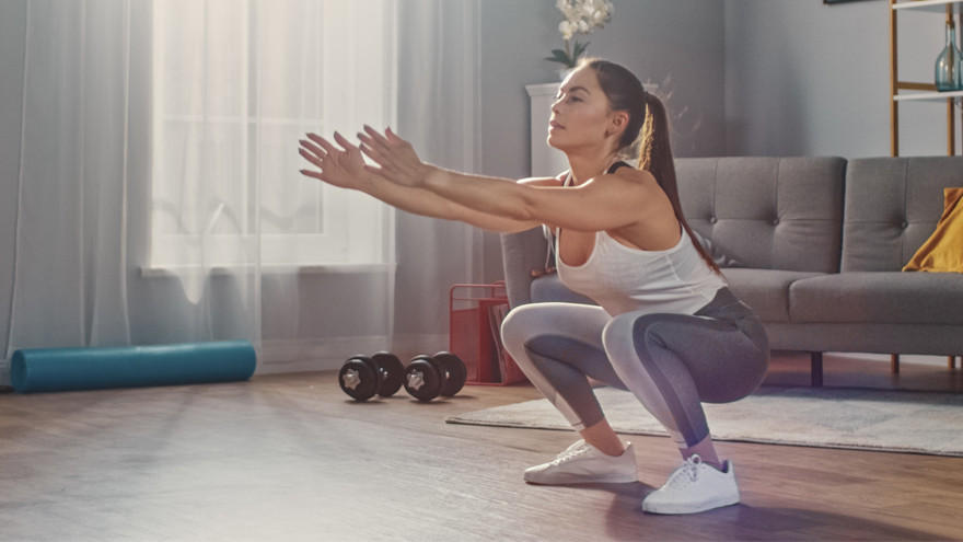 Femme en squats dans un salon aménagé pour le sport.