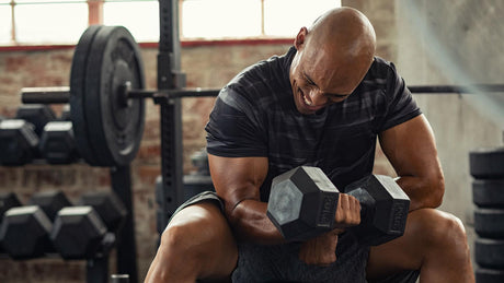 Man doing dumbbell curls in gym.