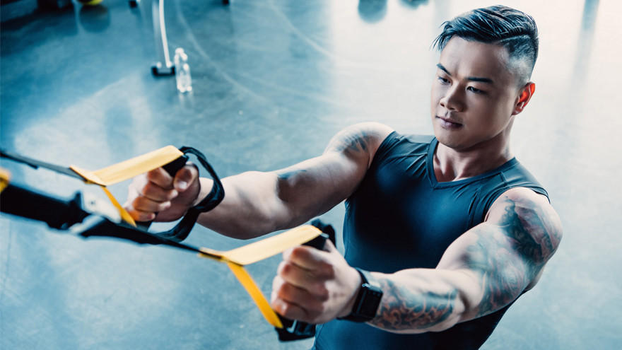 Man training with TRX suspension straps in gym.