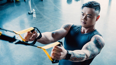 Man training with TRX suspension straps in gym.