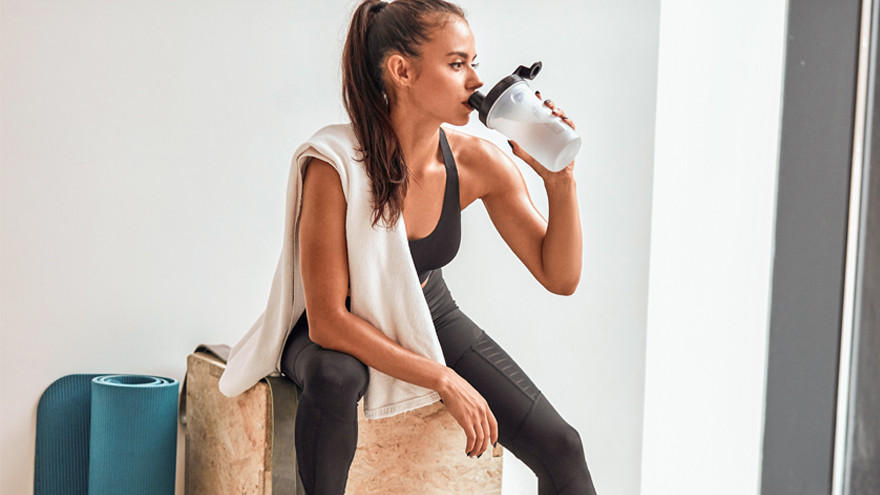 Femme sportive buvant un shaker après l’entraînement.