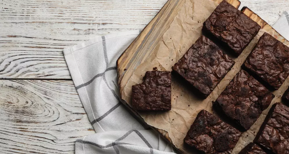 Chocolade brownies op houten plank met bakpapier.