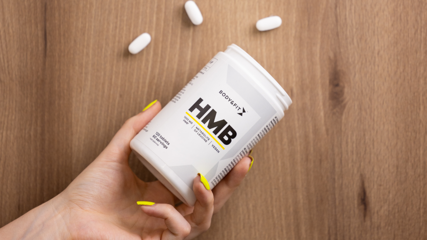Body&Fit HMB supplement in hand met gele nagels.