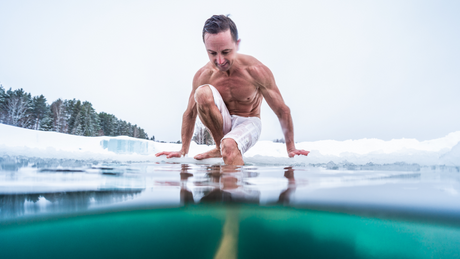 Homme torse nu entrant dans un lac glacé.