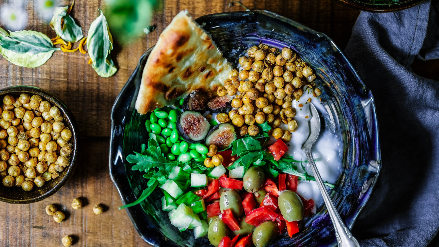 Colorful plant-based meal bowl with chickpeas, veggies, and flatbread.