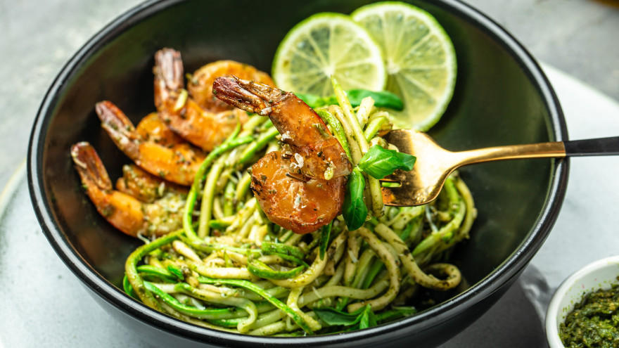 Zucchini noodles with grilled shrimp and lime slices.