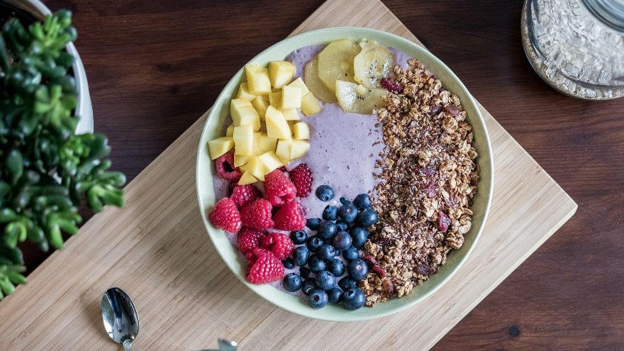 Bol de smoothie violet avec fruits frais et granola.