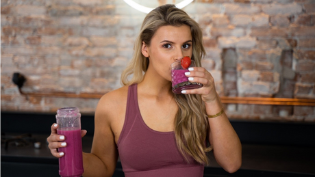 Femme buvant un smoothie rose à la fraise.