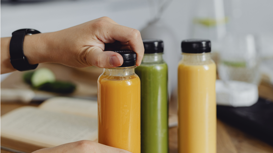 Main ouvrant une bouteille de jus coloré.