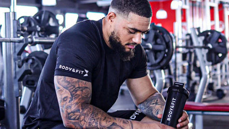 Homme tatoué au repos en salle de sport avec un shaker Body&Fit.