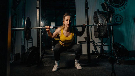 Woman doing heavy barbell squats in the gym.
