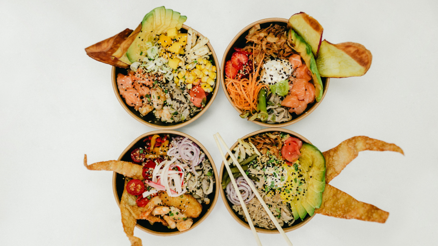 Vier kleurrijke poké bowls met verse toppings.