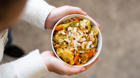 Bunte vegetarische Bowl mit Reis, Gemüse und Kokosraspeln.