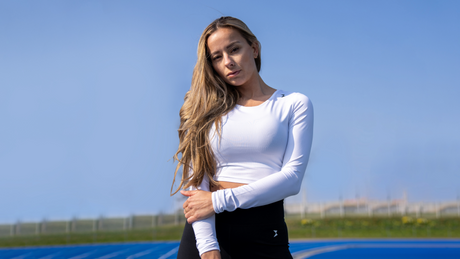 Vrouw in sportoutfit op blauwe atletiekbaan.