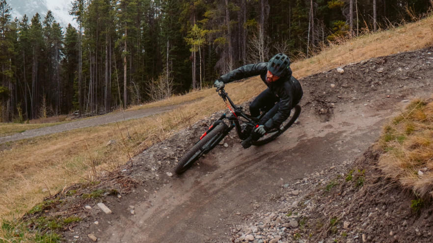 Mountainbiker fährt rasant durch Kurve im Wald.