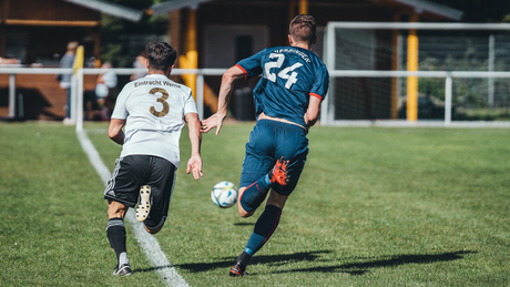 Deux joueurs de football courant vers le ballon sur le terrain.