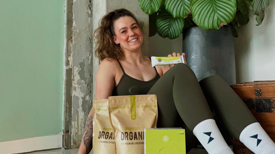 Donna con prodotti Body&Fit Organic sorridente a casa.
