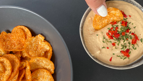 Protein-Chips werden in cremigen Dip mit Kräutern getaucht.