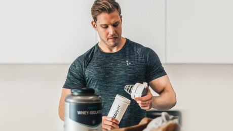 Man preparing protein shake with Body&Fit shaker and whey isolate.