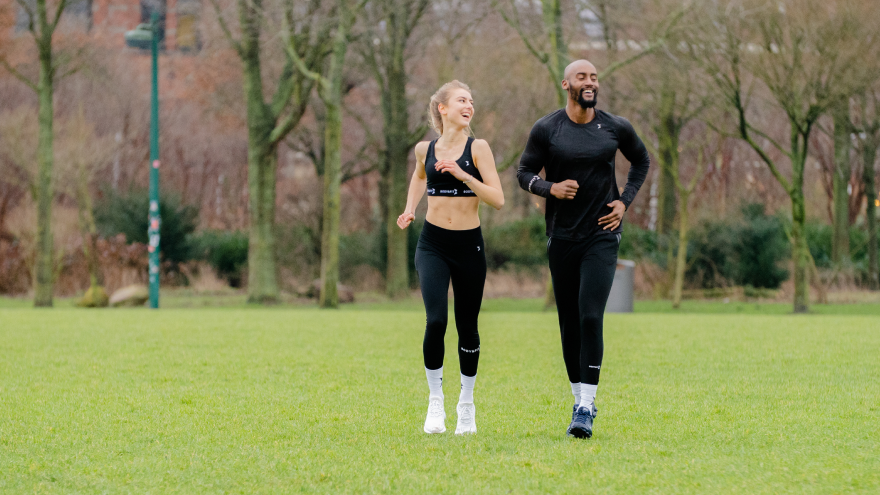 Man and woman jogging together in green park.