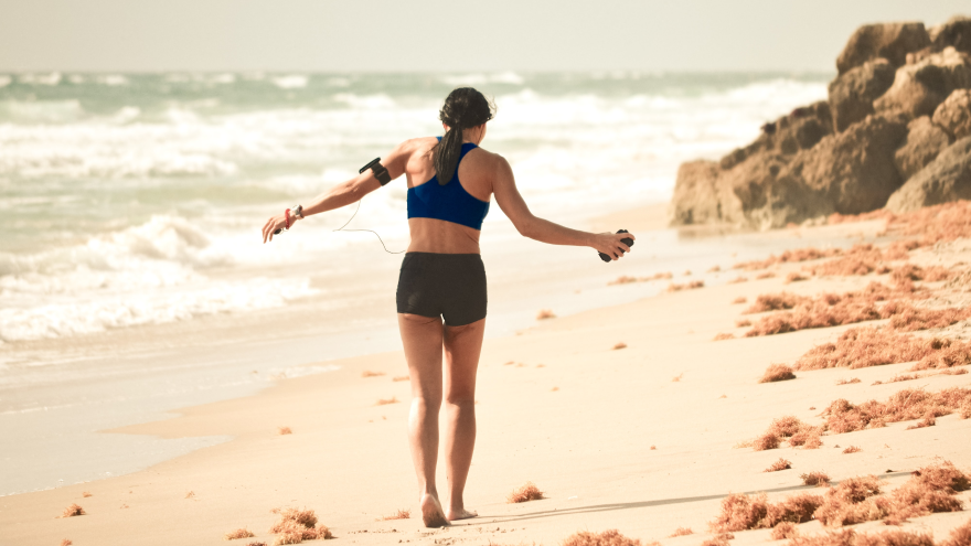 Woman exercising with jump rope on the beach.