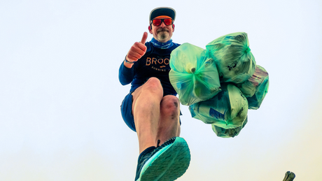 Coureur ramassant des sacs poubelle avec pouce levé.