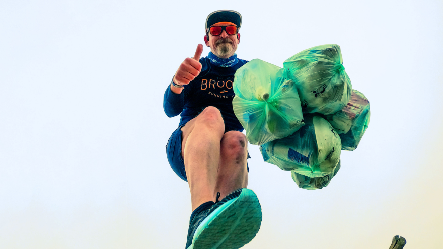 Hardloper met vuilniszakken tijdens plogging activiteit.