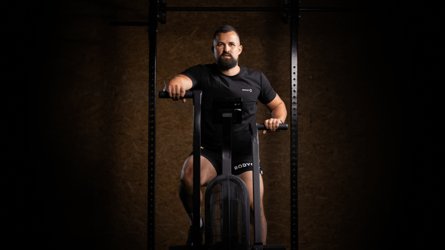 Man on air bike in gym wearing Body&Fit apparel.