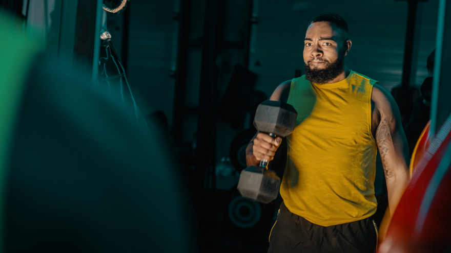 Man tilt dumbbell tijdens intensieve krachttraining.