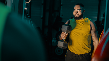 Man tilt dumbbell tijdens intensieve krachttraining.