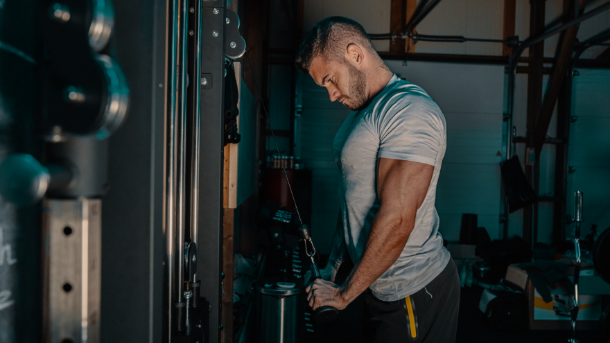 Man training triceps on cable machine.