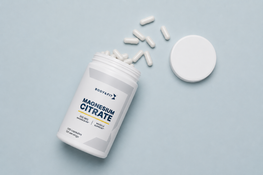 Body & Fit Magnesium Citrate supplement jar open with white capsules spilling out on a light blue background