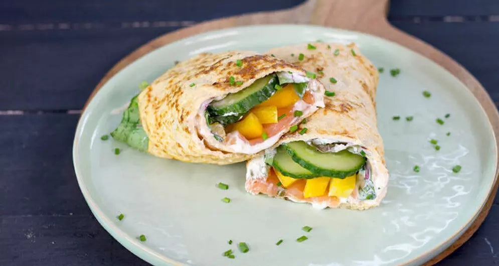 Healthy veggie and salmon wrap on green plate.