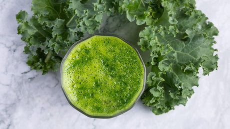 Grüner Smoothie mit frischem Grünkohl auf Marmortisch.