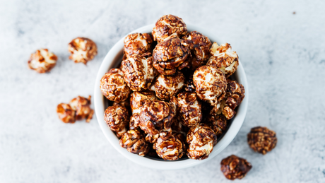 Chocolate-covered caramel popcorn in white ceramic bowl.