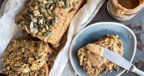 Geschnittenes Vollkornbrot mit Körnern und Erdnussbutter auf grauem Teller.